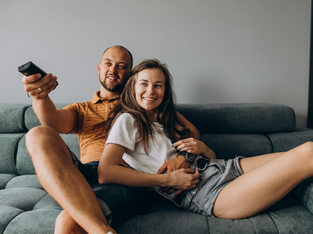 Casal assistindo IPTV em um sofá.