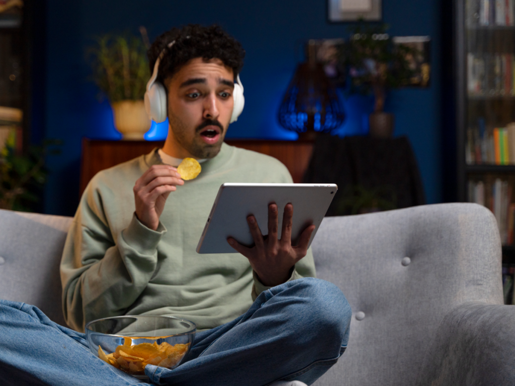 Homem surpreso segurando um tablet, assistindo a algum programa da lista IPTV.