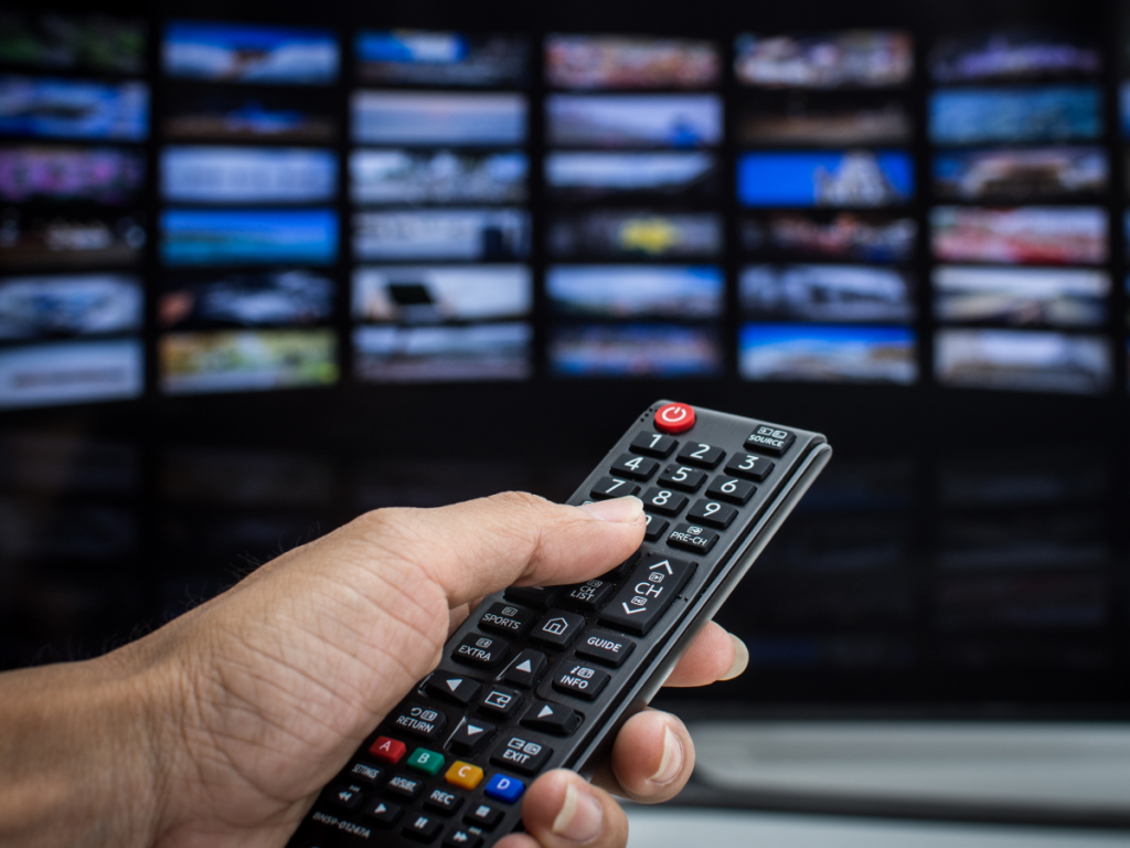 Mão segurando um controle remoto de TV, representando a solução de problemas comuns com o IPTV Smarters Pro.
