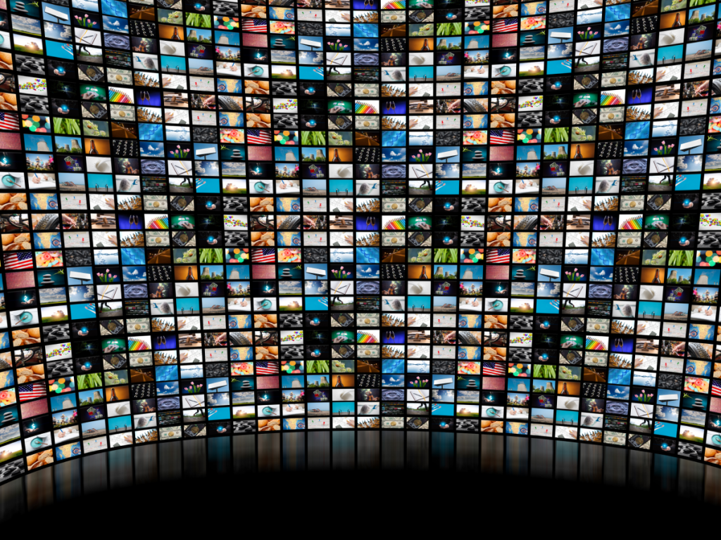 Painel curvo com centenas de miniaturas de vídeos exibidas em uma tela gigante, representando a diversidade de conteúdos disponíveis para assistir filmes online grátis via plataformas de streaming ou IPTV.